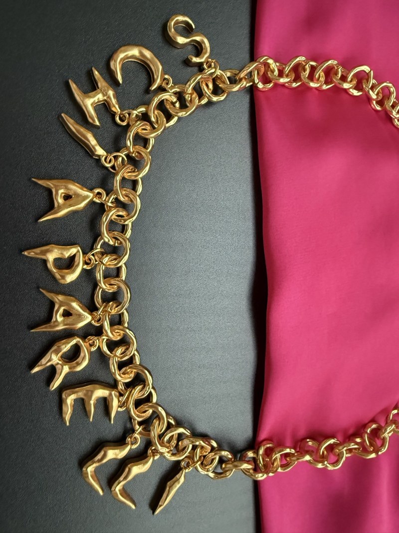 Золотистое колье с подвесками в виде букв Schiaparelli