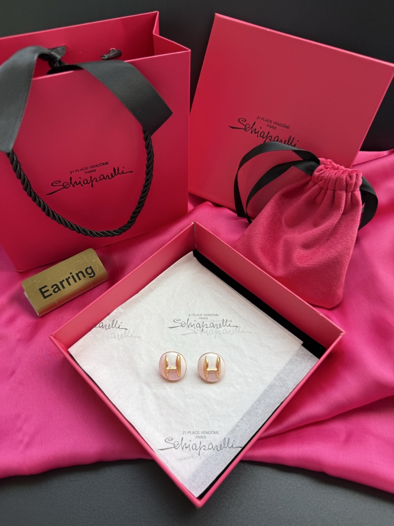 Серьги с золотым логотипом H на белом фоне Schiaparelli
