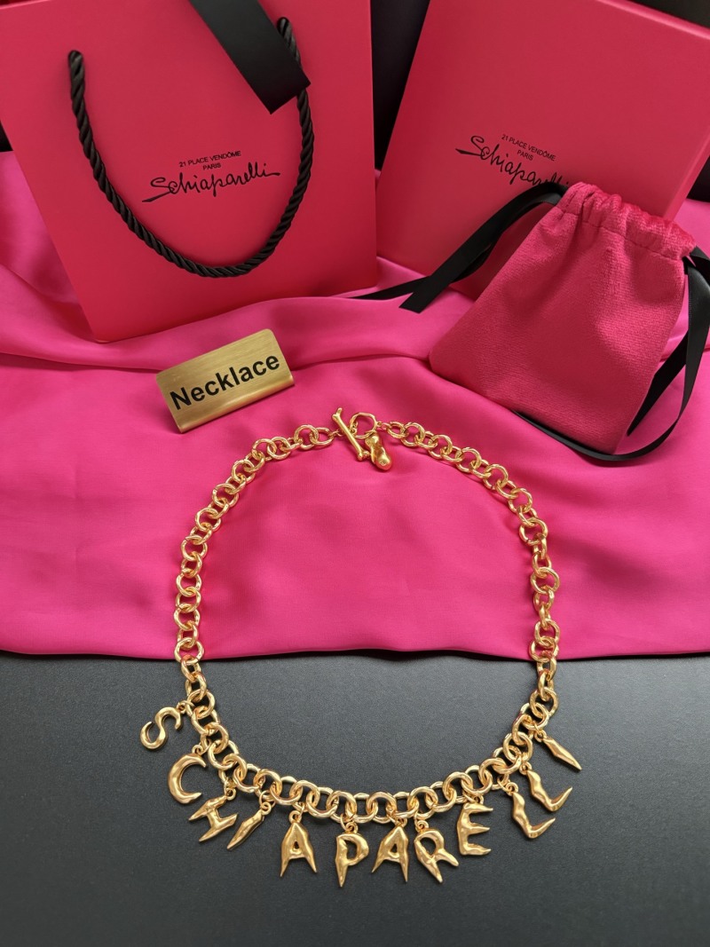 Золотистое колье с подвесками в виде букв Schiaparelli